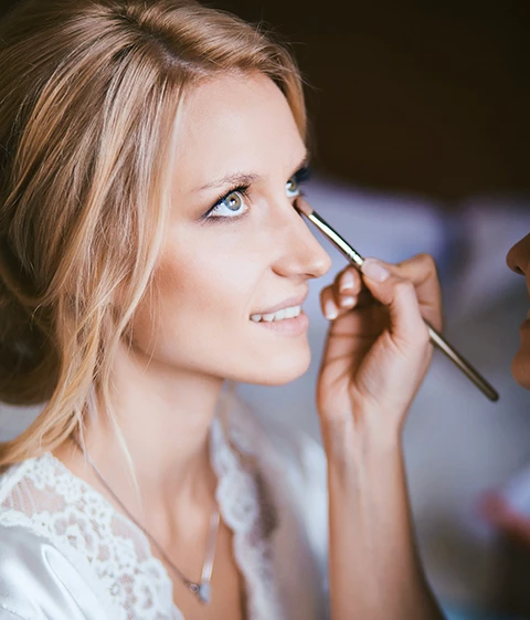 A bride getting her makeup done on her wedding day