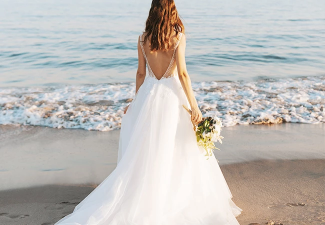 Bride on the beach looking at the sea