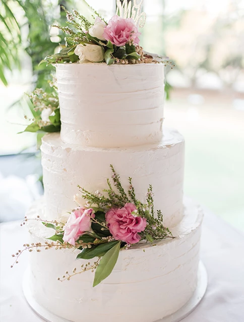 A white three-tier wedding cake with pink flowers